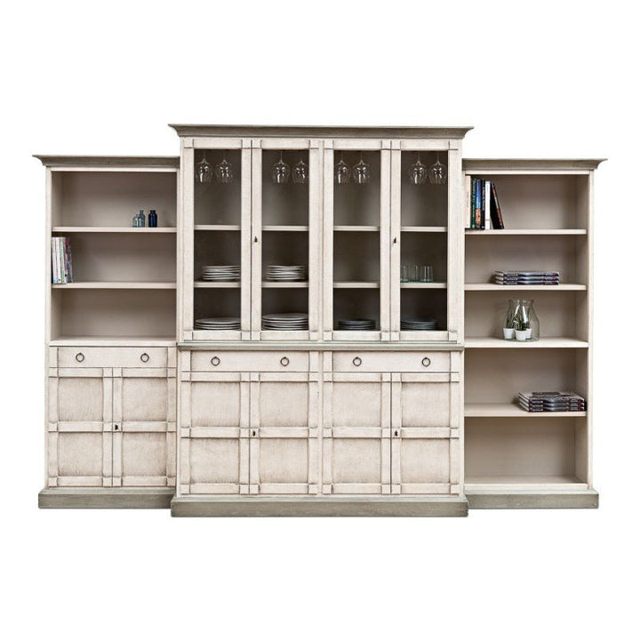 The Sarreid 4 Piece Full Wall Unit Bookcase in White & Grey is a transitional-style unit featuring a sizable, elegant wooden bookshelf and cabinet set. The central cabinet includes glass doors and shelves designed for hanging wine glasses, while the side units provide open shelves for books and various items. The lower section has closed cabinets and drawers for additional storage.