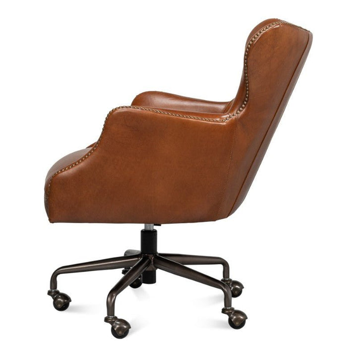 Side view of the Sarreid Andrew Jackson Desk Chair in vintage Havana leather, featuring armrests, a high back, nailhead trim, and a swivel base with five wheels. This chair boasts a classic and elegant transitional design ideal for an office setting.