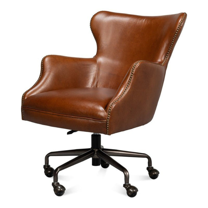 The Andrew Jackson Desk Chair in Havana Leather by Sarreid is an elegant brown leather office chair that features nailhead trim, a high wingback design, padded armrests, and a swivel base with five caster wheels for mobility. This chair showcases vintage Havana leather that perfectly complements its refined transitional design.