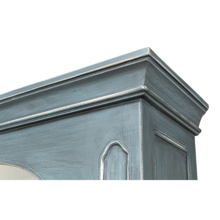 Close-up image of the top corner of the Banner Bungalow Bookcase by Sarreid, finished in a blue-gray color. Crafted from Russian pine, it features decorative molding and a carved panel design on the side.