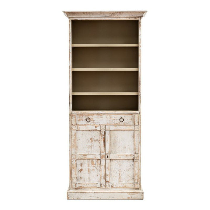 The Bookcase With Doors, Disrupted White by Sarreid is an exquisite tall, distressed white wooden cabinet that evokes the feel of a Rustic White Bookcase. It boasts four open shelves, one middle drawer with two round knobs, and a double-door cupboard at the bottom. Crafted from solid pine, this empty bookcase radiates a rustic vintage charm.