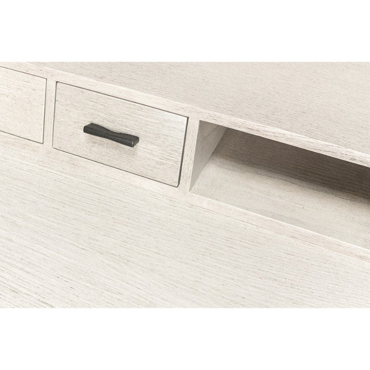 Close-up view of a section of the Covet Desk by Sarreid in an Ivory Bianca finish. It boasts practical functionality with a small rectangular drawer featuring a dark handle on the left and an open cubby space on the right. The surface has a textured, grainy finish, exemplifying modern elegance.