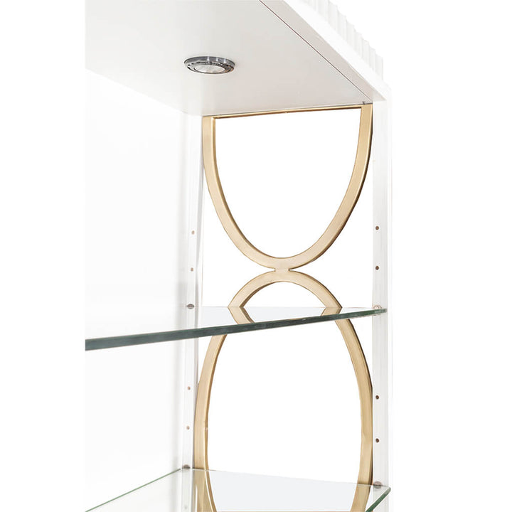 A close-up view of the East Camden Deck by Fairfield Chair reveals its elegant design, featuring clear glass shelves and stylish gold metal accents on the sides. This sophisticated display shelf includes a small, round built-in three-way touch light fixture on the top for added functionality. The background is a plain white, highlighting its chic appearance.