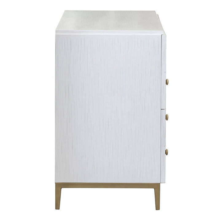 Side profile of the contemporary East Camden Lateral File Cabinet by Fairfield Chair, showcasing a sleek white finish with a textured facade. It features three small round antique brass knobs on the right side and stands gracefully on gold metal legs. This piece effortlessly embodies casual elegance.