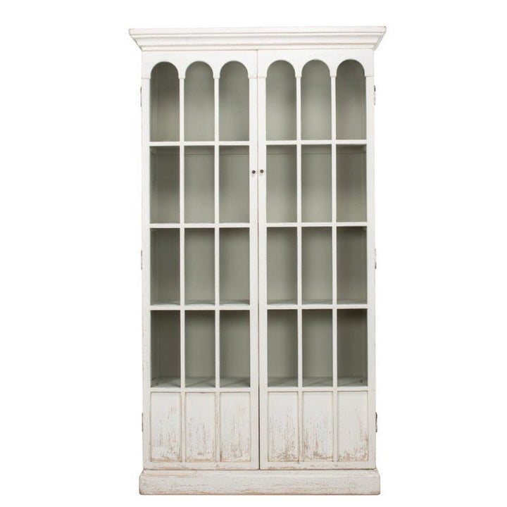 The Edgar Allan Glass Bookcase by Sarreid is a tall, white, rustic cabinet with glass-paneled doors featuring an arched design at the top panels and two door handles. Crafted from reclaimed pine, it boasts four visible shelves inside and a distressed finish for vintage charm—an exemplar of true traditional design.