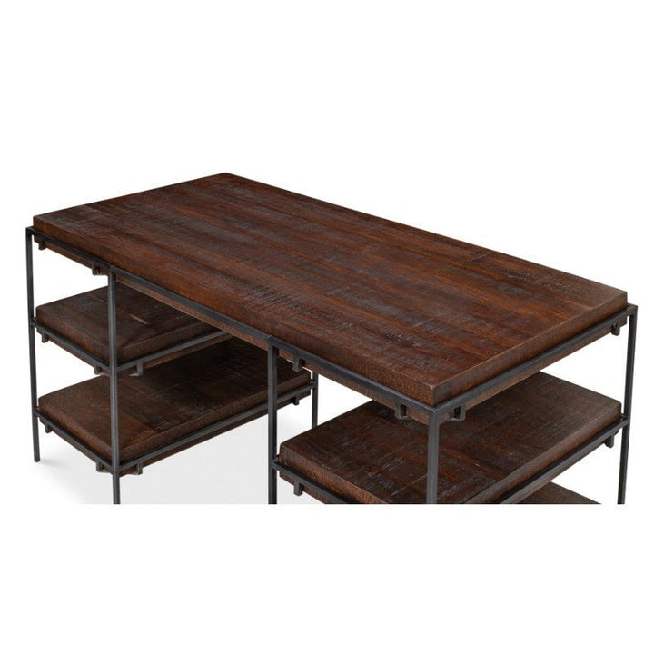 The Ernest Desk by Sarreid is a modern and industrial rectangular wooden table, featuring a rich, dark mango wood finish. This home office desk is supported by a sturdy iron frame and includes two lower shelves on each of its longer sides for additional storage, which are crafted from the same dark mango wood as the tabletop. Measuring 60 inches, this piece perfectly blends functionality with contemporary design.