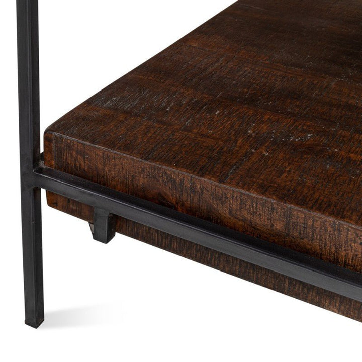 Close-up of the Ernest Desk by Sarreid, featuring a rich, dark brown mango wood surface with visible grain patterns, reminiscent of an industrial style. The textured wooden desk is securely mounted within a black iron frame that has a matte finish and simple, clean lines.