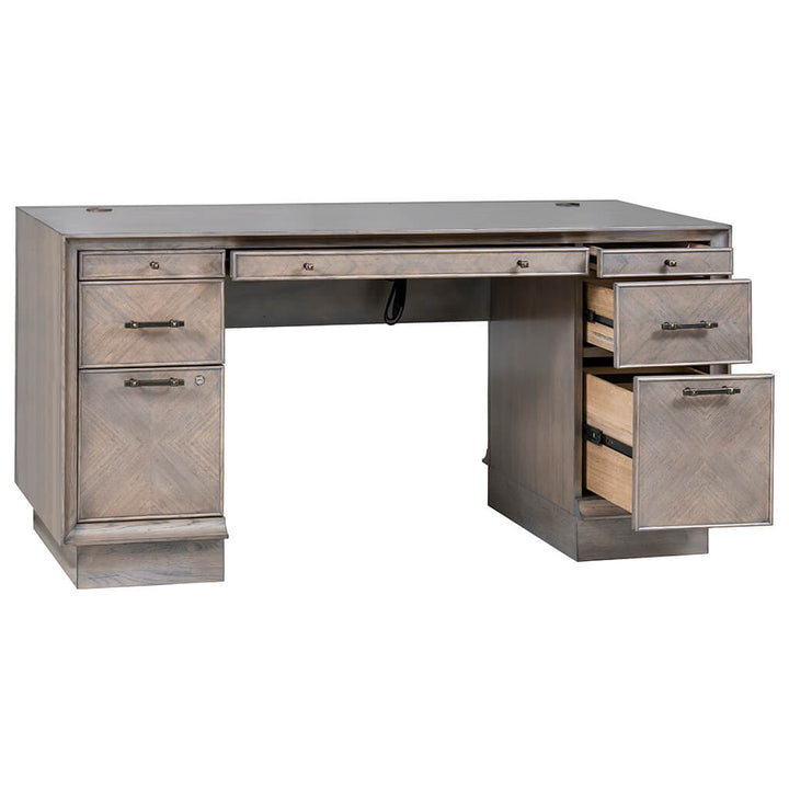 The Expedition Pedestal Desk 60" by Fairfield Chair is a wooden desk with a flat top, featuring multiple drawers. Two drawers on the right side are open, showcasing inner compartments. The desk has a classic design with an Art Deco influence, a weathered gray finish, and metal handles on the drawers.