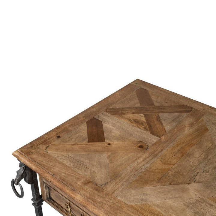 Close-up of the Game Of Thrones Desk by Sarreid, featuring a distinctive intersecting pattern on the wooden tabletop. This rustic piece is crafted from reclaimed old wood and boasts a natural wood finish with dark metal corner accents. The clear surface stands out, free of any objects.