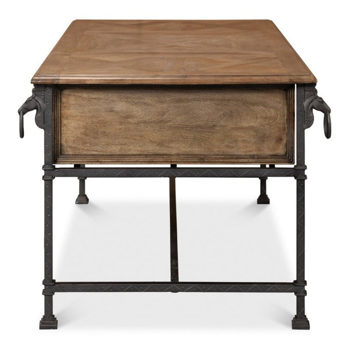 Front view of the Game Of Thornes Desk - Sarreid, a rectangular wooden table crafted by Sarreid. The desk features intricate detailing on its metal legs, with a front panel made of solid reclaimed old wood. The legs are adorned with animal head accents at the top corners where they meet the table, highlighting its distinctive design.