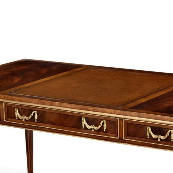 The Aston Court Gilt Mahogany Writing Desk boasts a sophisticated polished finish and an elegant leather top. This rectangular wooden desk features intricate gold handles on its two front drawers, exemplifying classic and luxurious craftsmanship. The straight, slender legs further enhance its refined appearance.