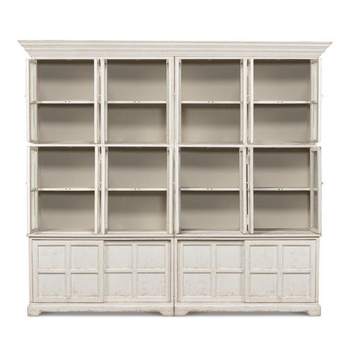 Introducing the Glass Front Bookcase - Sarreid from Sarreid, a large, vintage-style white bookcase with a distressed finish. Part of our farmhouse collection, it features twelve open shelves arranged in three vertical columns and four horizontal rows. The bottom section is adorned with six paneled cabinet doors, three on each side, exuding classic country style charm.