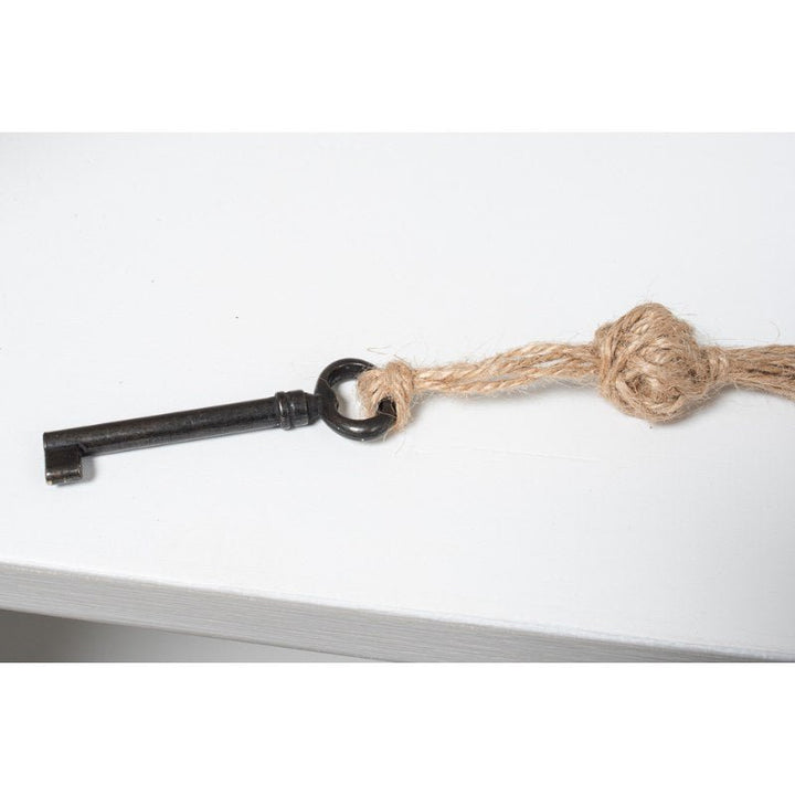 A vintage skeleton key attached to a piece of rough twine is placed on a white surface, reminiscent of the elegant design found in Sarreid's Harper Glass Front Bookcase. The twine is knotted near the key's circular handle, enhancing the image's simple and minimalistic composition.