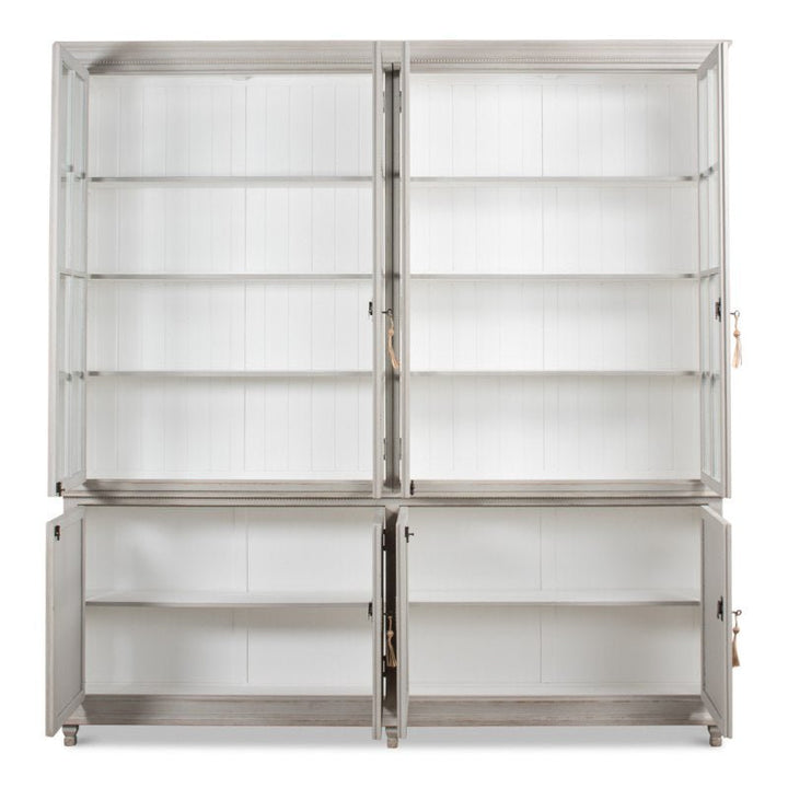 The Harper Glass Front Bookcase by Sarreid is a tall, white wooden cabinet featuring two glass doors on the top section and two solid doors on the bottom. With its elegant design and multiple shelves for ample storage or display, it is ideal for a clean, modern interior.