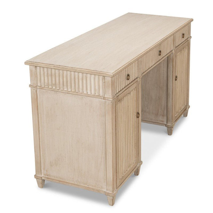 The Inspire Desk, Stone Grey 53" by Sarreid features a light, distressed Stone Grey finish with a flat rectangular top and fluted accents on the front and sides. It includes multiple drawers with round knobs for storage and stands on four tapered legs. This compact piece adds a modest yet classic touch to your space.