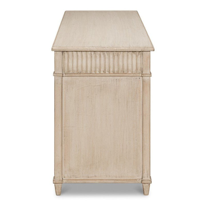 Side view of a rectangular, vintage-style wooden dresser with a distressed off-white finish. The dresser features fluted detailing along the top edge and small, tapered feet. The overall compact design is simple and elegant, reminiscent of the timeless charm found in Sarreid's Inspire Desk, Stone Grey 53".