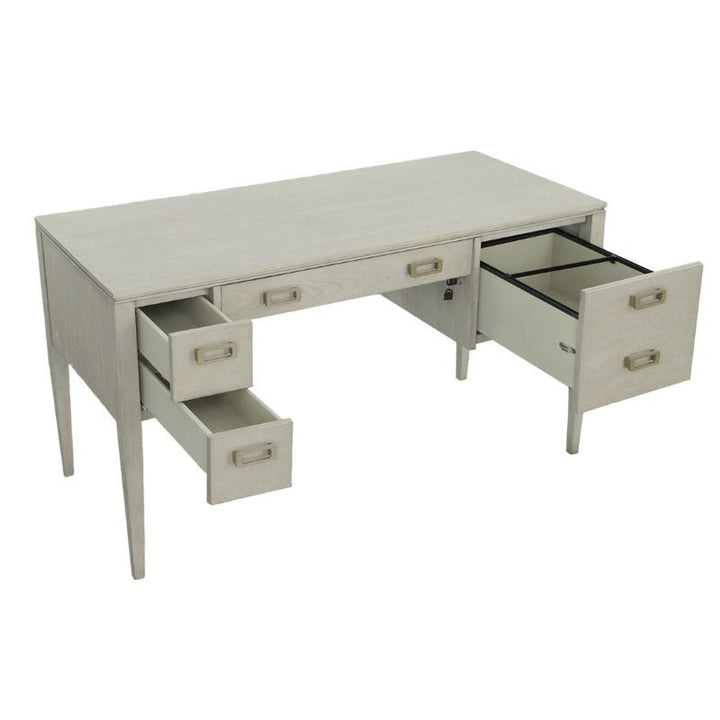 The Libby Langdon Patton Desk 54" by Fairfield Chair is a light wood office desk with a rectangular tabletop and a sheer dove gray finish. It features five drawers adorned with elegant brass hardware: three smaller drawers on the left, one central drawer beneath the tabletop, and one larger drawer on the right. Several drawers are open.