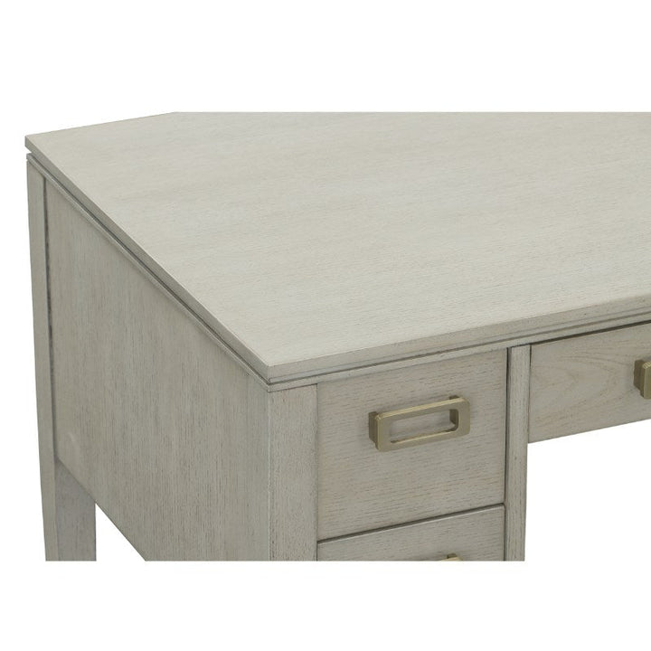 A close-up of the Libby Langdon Patton Desk 54" by Fairfield Chair reveals its sheer dove gray finish, showcasing two drawers with brass hardware on one side. The desk boasts a smooth, flat surface and maintains a minimalist aesthetic.