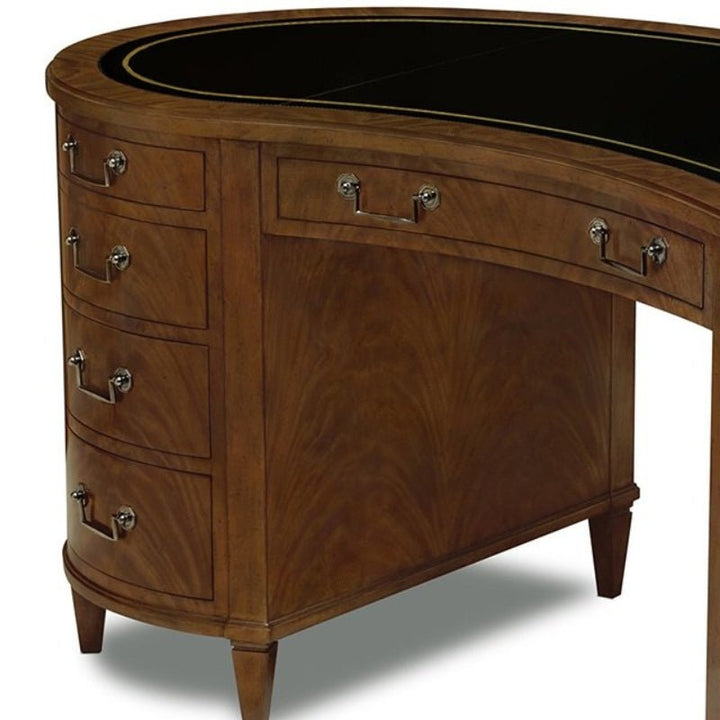 The Mahogany Kidney Desk from Aston Court features multiple drawers with shiny metal handles, a black top surface, and is supported by four tapered legs. Crafted from rich, polished bleached crotch mahogany, this elegant desk highlights visible grain patterns.