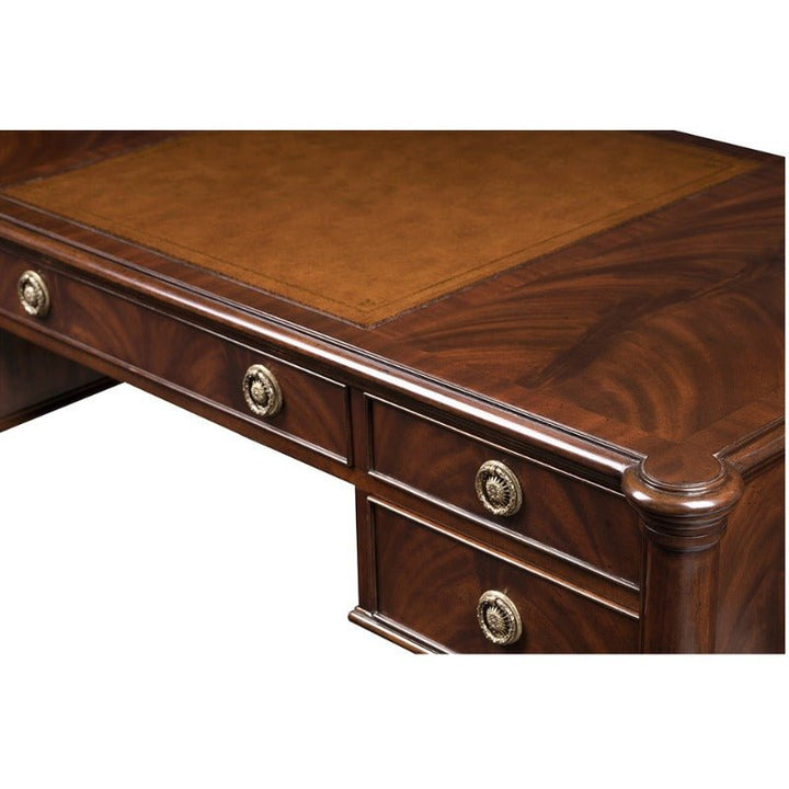 A close-up view of the ornate Mahogany Lady's Desk from Aston Court, featuring polished dark wood with brass handles on the drawers. The desk is accented by an antique brown leather inlay on the writing surface.