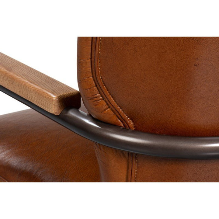 Close-up of the Parker Office Chair in Vintage Havana Leather by Sarreid, highlighting its textured upholstery. The chair showcases a smooth, curved black metal frame and wooden armrest details, blending various materials and textures in the design. The use of elegant Vintage Havana Leather adds a sophisticated touch.