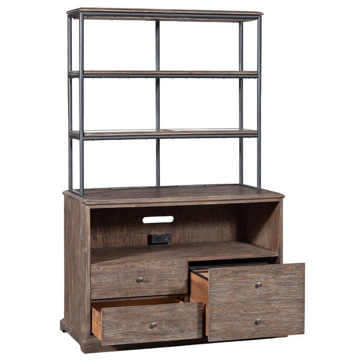 The Rustique Lateral File Cabinet by Fairfield Chair exudes rustic elegance with its wooden hutch and black metal frame shelving. Featuring three open shelves, a spacious middle surface with a cable management hole, and three drawers for storage—two of which are partially pulled out—the distressed wood finish adds to its charm while offering modern functionality.