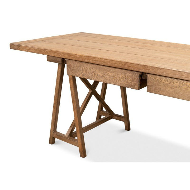 Introducing the Sawhorse Desk by Sarreid: an 87-inch wooden desk crafted from reclaimed pine, featuring a rectangular top and foldable trestle-style legs. It includes a hidden drawer just below the tabletop and boasts a natural polished old pine finish that highlights the grain and texture, bringing rustic charm to any room.