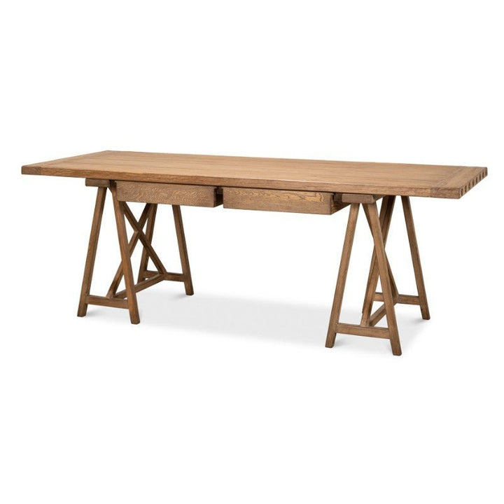 The Sawhorse Desk, Natural Polished Old Pine 87" - Sarreid, is a beautifully crafted wooden table made from reclaimed pine. It features a rectangular top with a natural wood finish and is supported by two trestle-style legs with diagonal crossbars on each side. A central drawer beneath the tabletop enhances its rustic charm and sturdy appearance, reminiscent of classic design aesthetics.