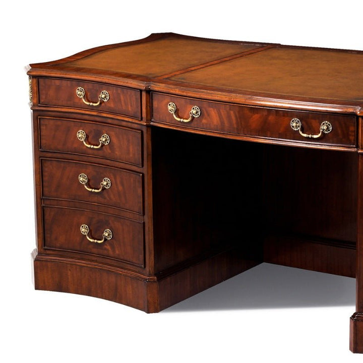 The Serpentine Writing Desk by Aston Court is an elegant piece featuring a curved front and a dark finish. It includes six drawers adorned with ornate gold handles, an open central area for legroom, and an antique brown leather top. Crafted from crotch mahogany, this desk's polished surface makes it an ideal addition to any office or study.