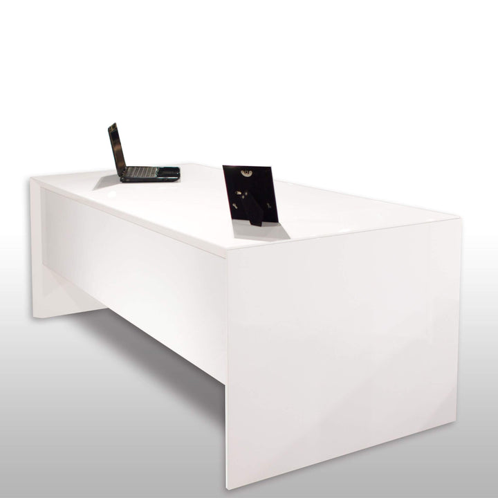 A sleek and modern Sharelle Bellini Desk by Sharelle Furnishings, finished in pristine white lacquer with a reflective surface, stands elegantly in the room. On the desk, an open laptop and a small black picture frame are placed. This White Lacquer Desk enhances the minimalist home office setup, set against a plain white background for a clean appearance.