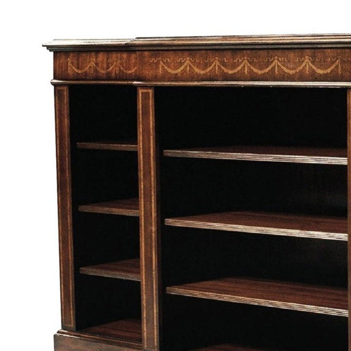 A picture of the Short Mahogany Bookcase from Aston Court, crafted in rich dark mahogany and adorned with intricate carvings along the top edge. This elegant piece features multiple shelves and open sides, revealing deep, rectangular compartments ideal for storing books or other items, elegantly showcasing its craftsmanship and compact design.