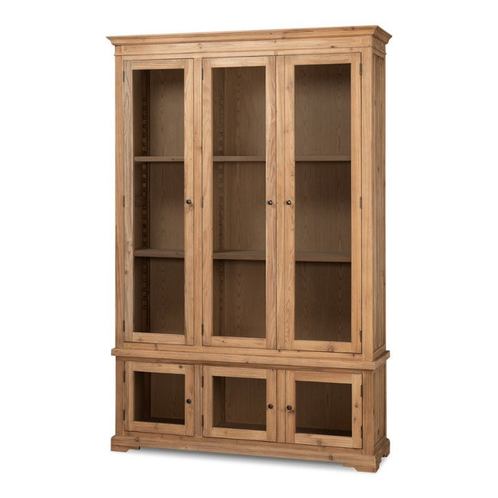 The Tanner Bookcase, Natural by Sarreid, is a tall wooden cabinet crafted from reclaimed pine with a natural brushed finish. It features six glass-paneled doors—three on the top section and three smaller ones on the bottom. The upper section has shelves, while the lower section offers additional storage space.