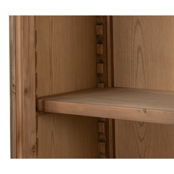 A close-up view of the Tanner Bookcase, Natural by Sarreid, showcasing its adjustable shelves. The image focuses on the side panel and the grooves used to secure the shelf in place. Made from reclaimed pine with a natural brushed finish, the craftsmanship of the joinery is clearly visible and exquisite.