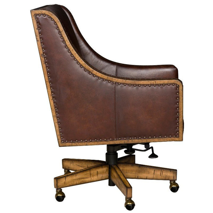 The side view of the Shard Office Swivel Chair - Fairfield Chair, a luxurious brown aniline leather office chair by Fairfield Chair, showcases elegant wooden accents and a stylish studded trim. It features a high back, armrests, and a wheeled base with casters for easy mobility.