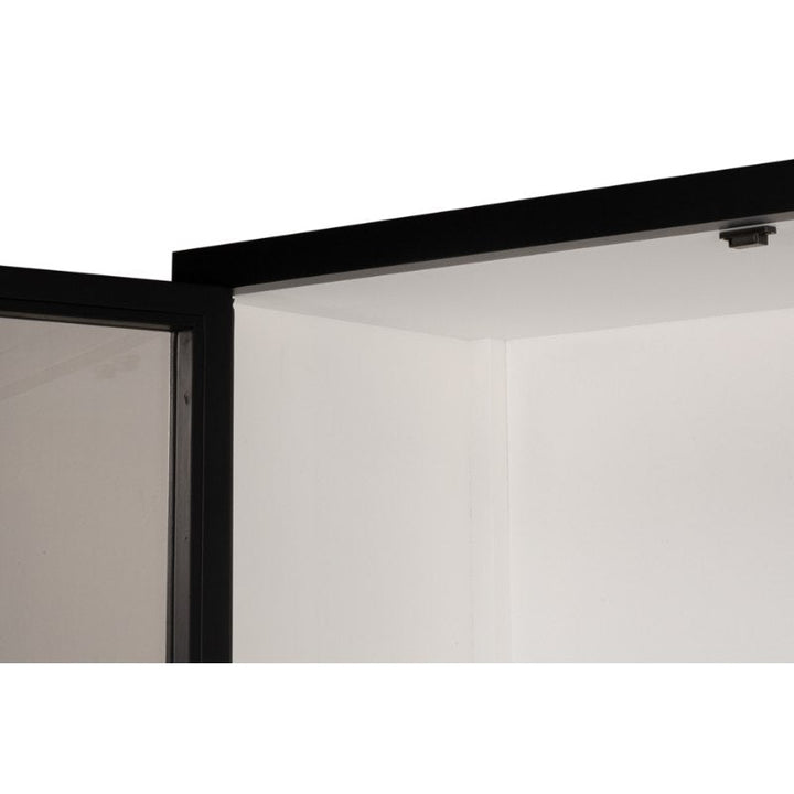 Close-up of a partially open black-framed glass door with a brushed black exterior. The door, hinged on the left, reveals the edge of the white interior wall and ceiling. The sleek framing complements any Sarreid Walker Bookcase, Black or other rustic elements in the space.