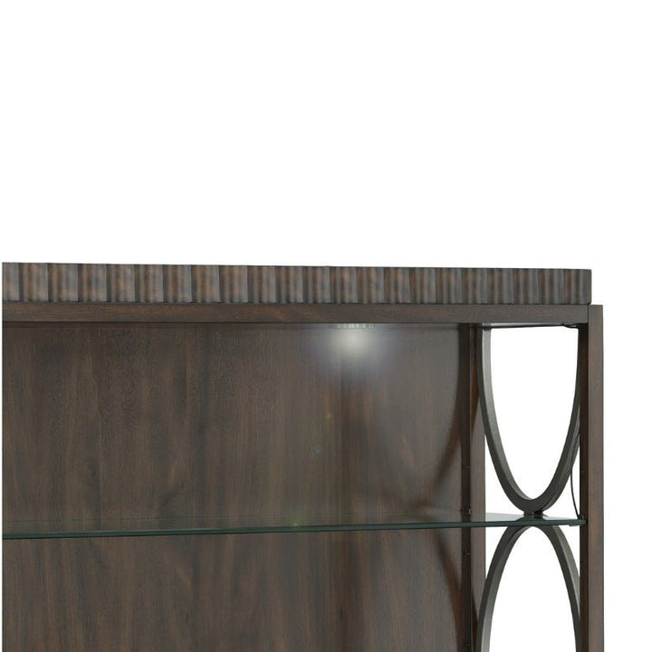 A close-up of the West Camden Deck - Fairfield Chair wooden display cabinet, crafted by Fairfield Chair, showcases adjustable glass shelves and metal decorative accents along the sides. The wood, finished in a rich Tahitian Pearl hue, highlights visible grain patterns while the metal framework boasts an elegant curved design.