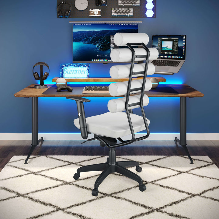 A modern home office setup featuring dual monitors on a wooden desk, the sleek Zuo White Office Chair - Unico with ergonomic lumbar support and cylindrical backrests, a gaming headset on a stand, and ambient blue LED lights. The workspace is placed on a white geometric-patterned rug.