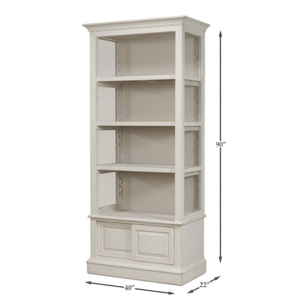 The Zoey Bookcase by Sarreid, featuring an antique white finish, stands tall at 90 inches and boasts dimensions of 40 inches wide by 22 inches deep. This elegant white wooden bookshelf includes three open shelves and a bottom cabinet with two panel doors, along with adjustable shelves for customized storage options.